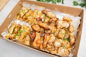 A platter filled with chicken skewers, wings, and breasts